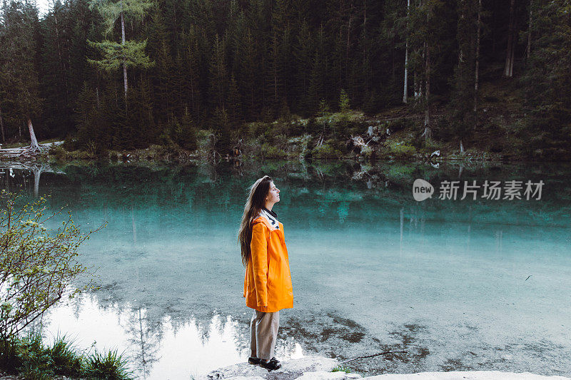 身穿雨衣的女人在Dolomites阿尔卑斯山的Lago Di braes享受日出